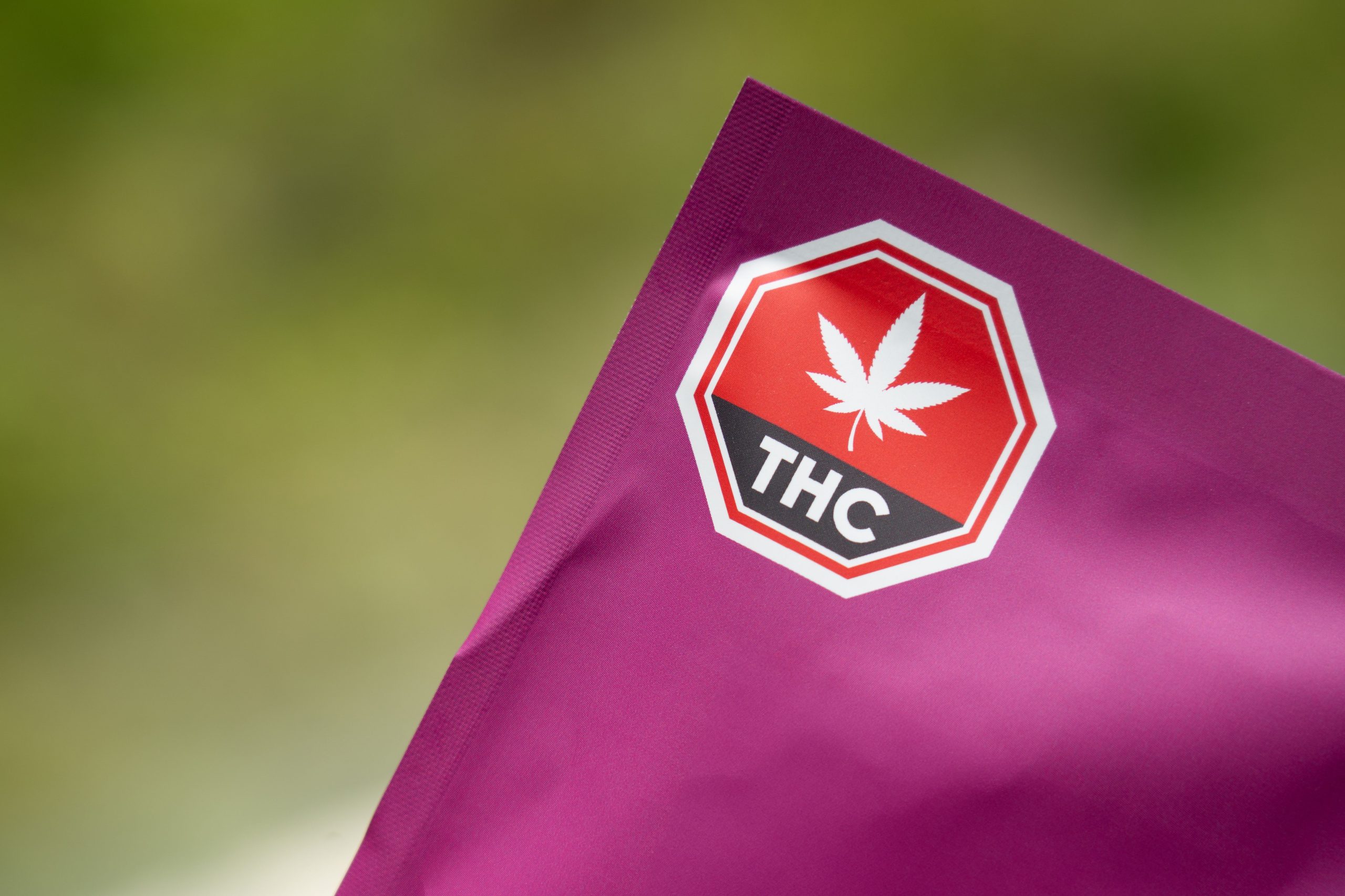 Close-up of cannabis packaging with a THC warning label on a purple background, highlighting safety and regulatory compliance